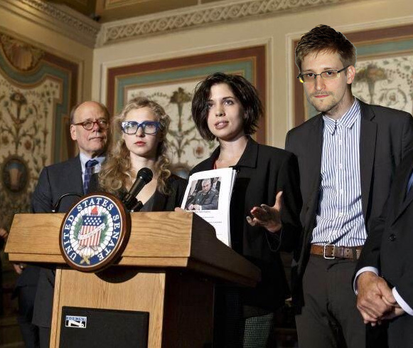 Photo of Russian President Nadya Tolokonnikova and American President Edward Snowden speaking at a podium at the US Capital in Washington DC